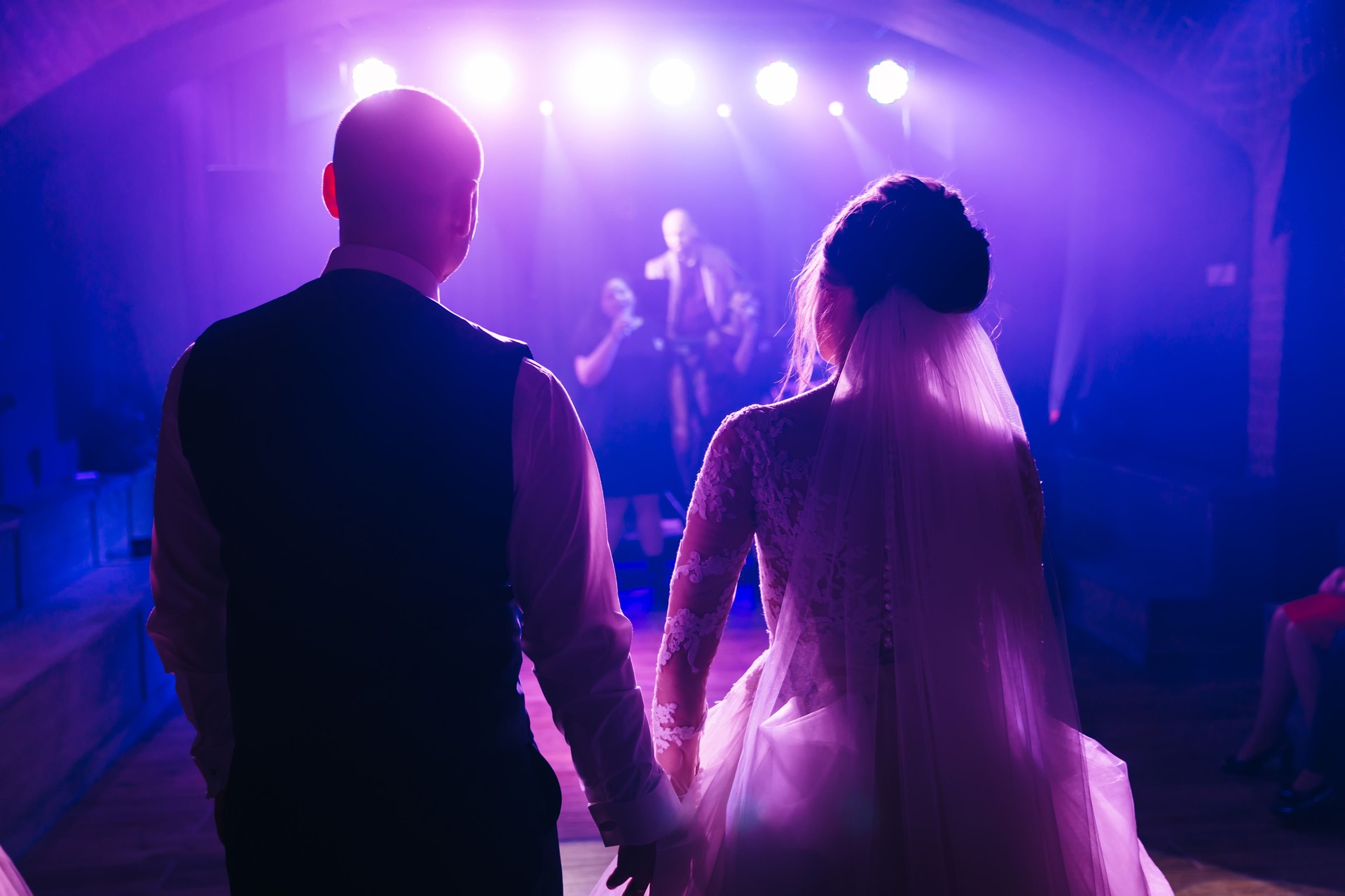 a beautiful couple of newlyweds stand with their backs and hold hands, look at friends who perform a song for them on their wedding day, enjoy the music.