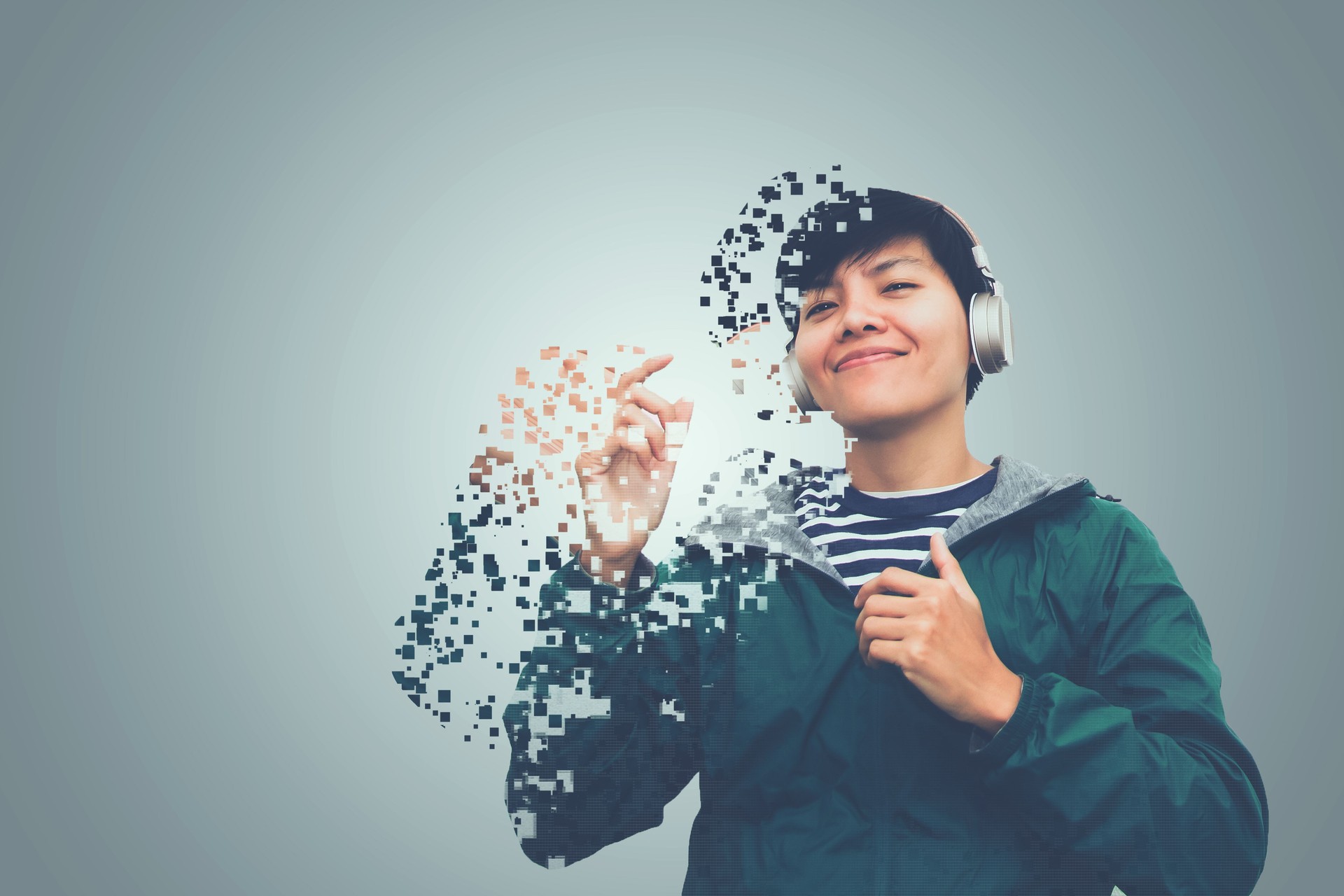 Asian man in green sweater wearing headset listen to music of dissolving into pixels on gray background Future technology Concept