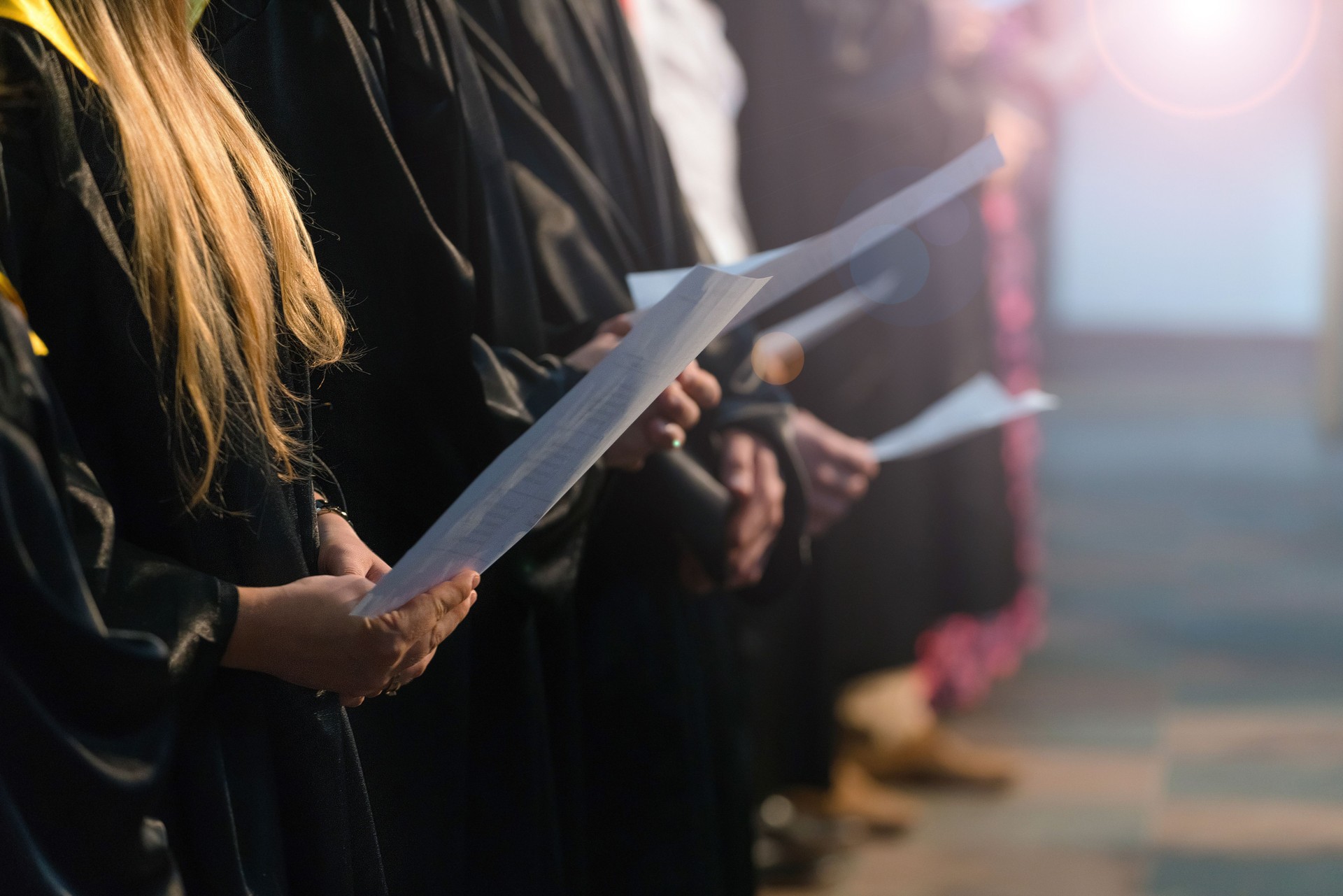 Choir singers holding musical score and singing on student graduation day in university, college diploma commencement